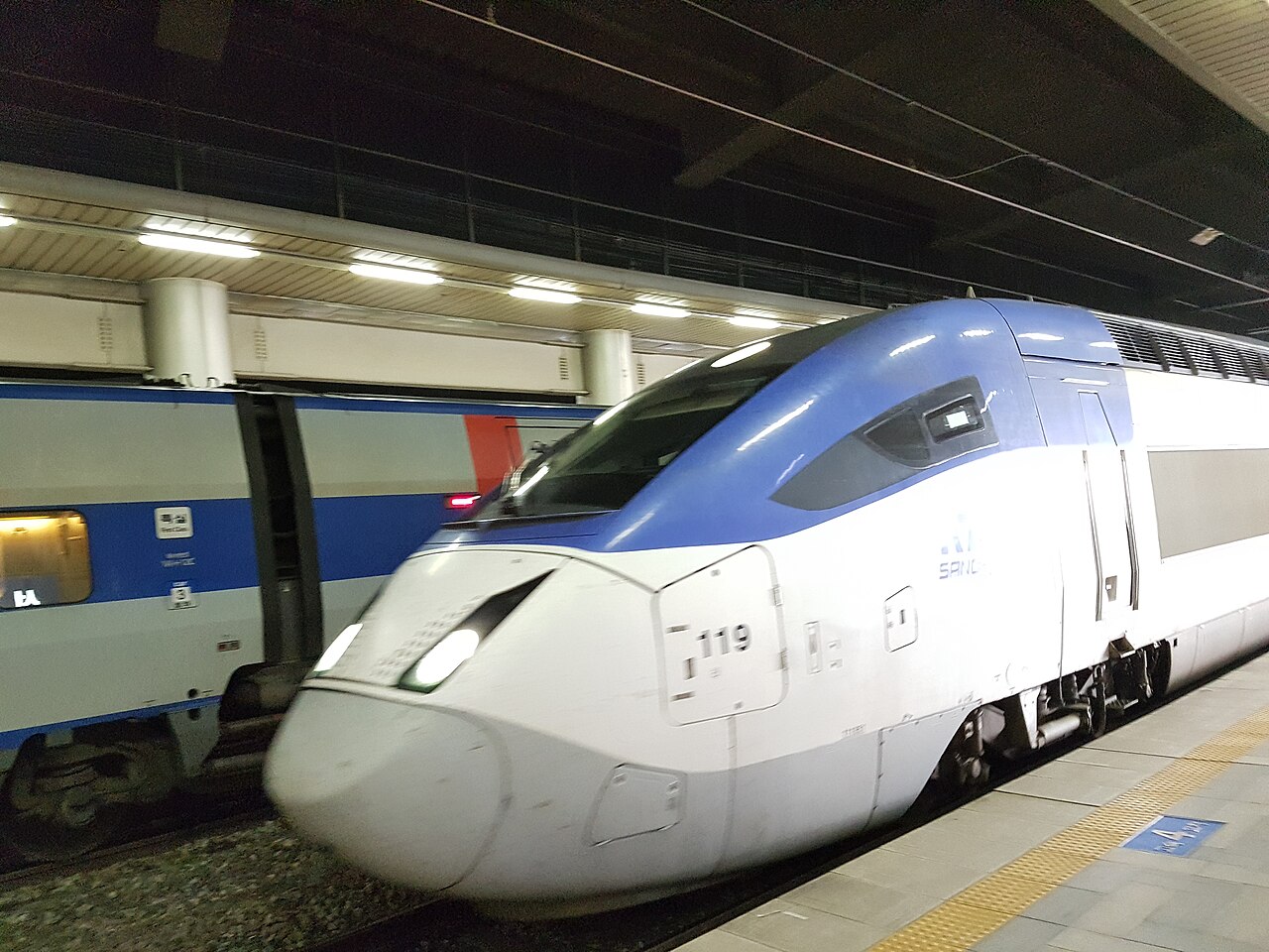 A blue and white KTX train beside a platform at Seoul Station.